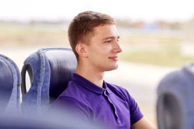 happy young man sitting in travel bus or train