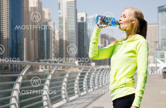 woman drinking water after doing sports outdoors