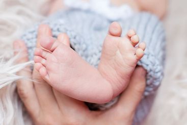 Parents holding in the hands little feet of newborn baby...