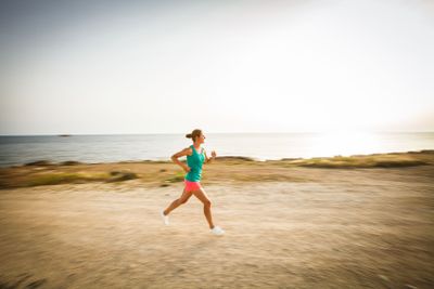 Young woman on her evening jog along the seacoast (motion...