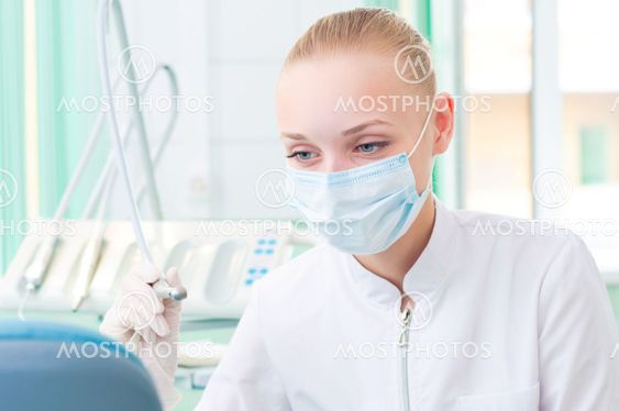 female dentists in protective mask holds a dental drill