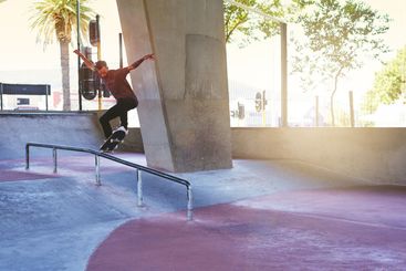Jump, skateboard and rail with man at park for urban,...