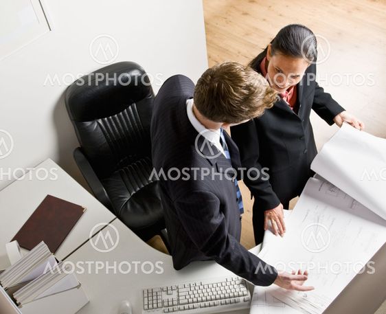 Business people reviewing blueprints together