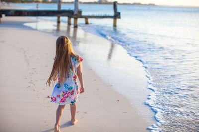 Adorable little girl walking at white tropical beach on...