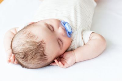 Portrait of an adorable baby with a pacifier sleeping in...