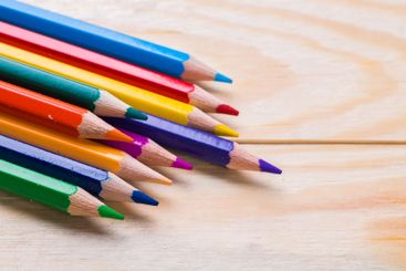 Brightly colored pencils arranged in a neat row on a...