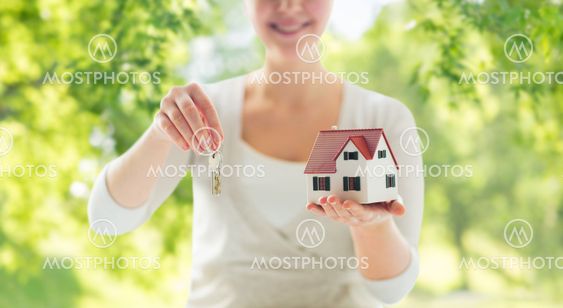 close up of hands holding house model and keys