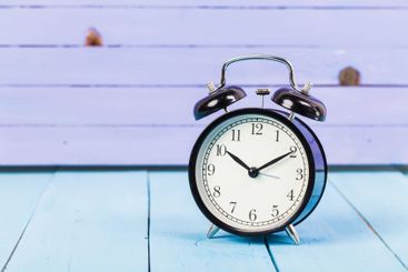 Black vintage alarm clock on wooden table