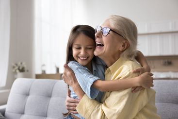 Excited loving grandma cuddling cute little...