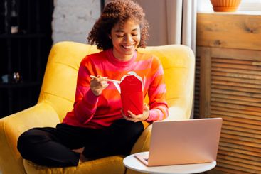 Cute African woman in sweater is sitting in yellow chair...