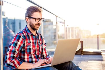 Businessman working from home on laptop, sitting on balcony