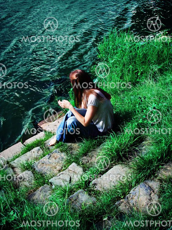 Young woman sitting on the riverbank