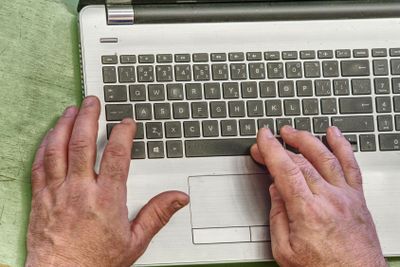 Hands of an old person on laptop keyboard. Grandfather...
