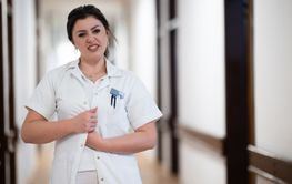 A dedicated nurse in uniform walks briskly down a...