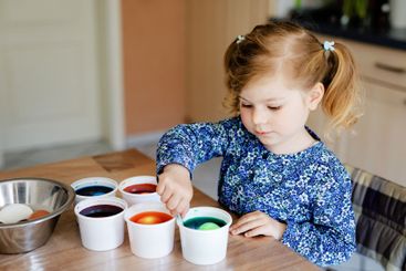 Excited little toddler girl coloring eggs for Easter....
