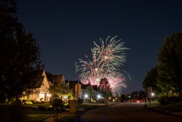 Evening fireworks over an American neighborhood with...