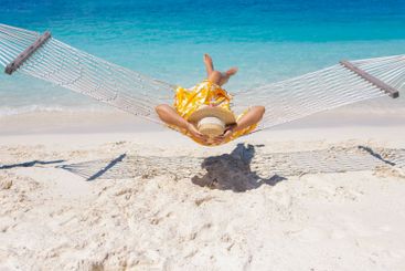 A young woman in a straw hat and a summer dress is lying...