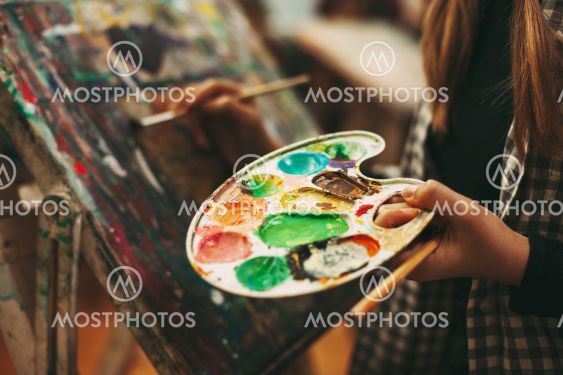 Palette with paints close-up in the hands of a girl, art...