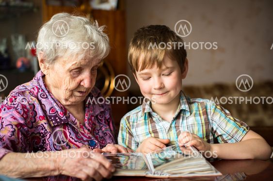 Elderly woman with her little grandson looking album