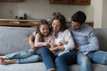 Happy parents, mom and dad cuddling, tickling little...