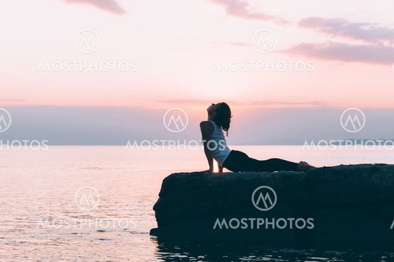 Young woman doing yoga by the sea