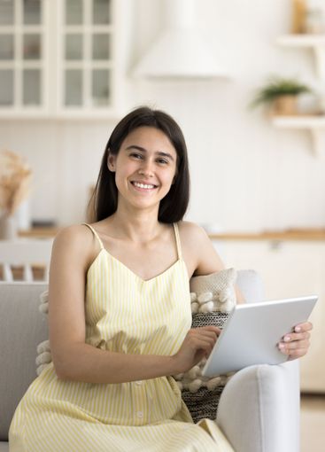 Portrait pretty smiling teen girl sitting on sofa...