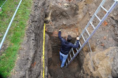 Archaeologist excavating a wall of a medieval building