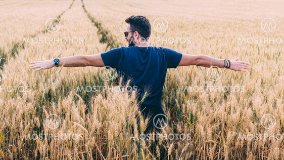 Young man resting in the wheat field at the sunset