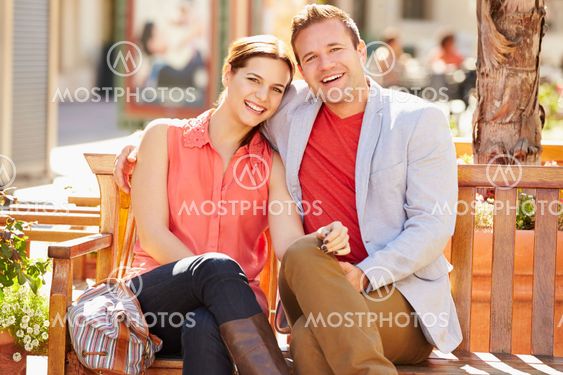 Young Couple Sitting On Seat In Mall Together