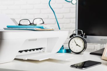 Desk setup with printer, clock, and office supplies in a...