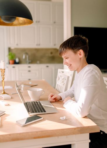 Smiling young businesswoman using laptop while sitting at...