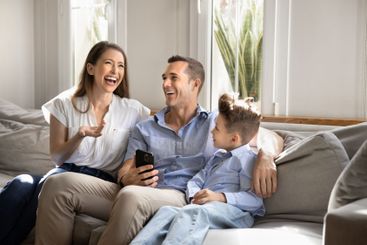 Cheerful mom, dad and little son boy resting on sofa