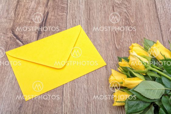 Yellow envelope and roses on a wooden background