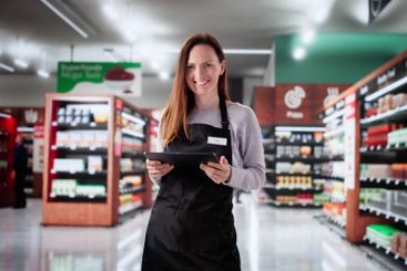 Smiling cashier at grocery store using tablet