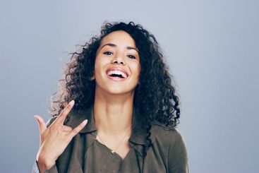 Portrait, smile and woman in studio with rock hand...