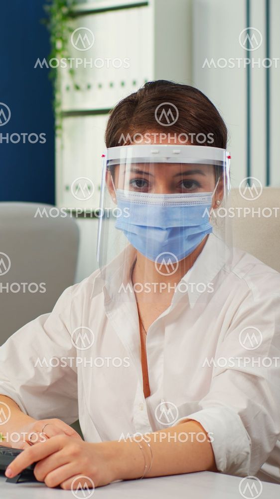Businesswoman with visor and mask talking in front of...