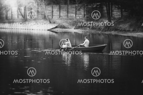 Black and white photo bride and groom riding on boat on...
