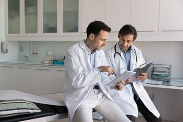 Two serious male doctor colleagues reading electronic...