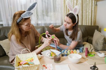 Mother and daughter decorating Easter basket at home.