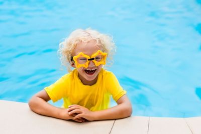 Child with goggles in swimming pool. Kids swim.