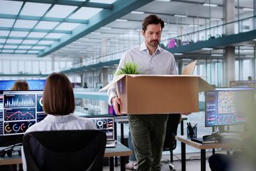 Employee in office packing up box after resignation meeting