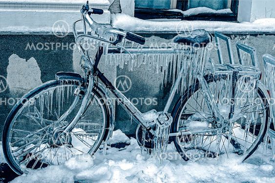 Blue look at ice icicles on a parked bicycle