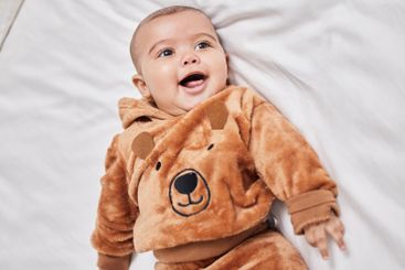 Happy, relaxing and baby on bed in nursery with...