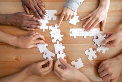 Close up multiracial people, team assembling puzzle,...