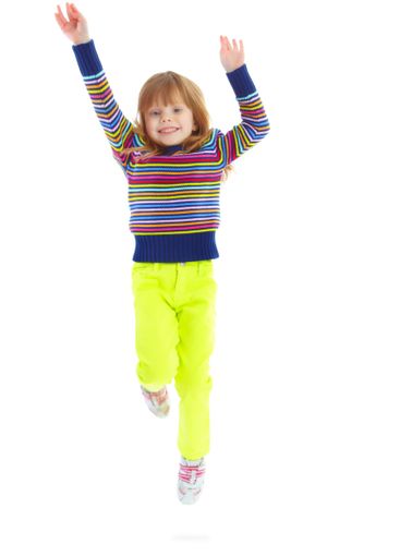 Portrait, smile and jump with girl in studio for child...