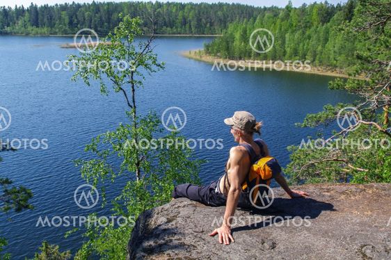 man with backpack sitting on cliff relaxing,
above the lake Yas