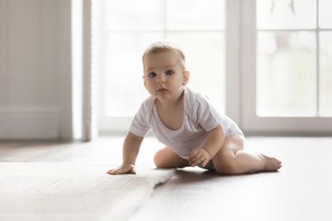 Happy active little baby crawl play alone on warm floor