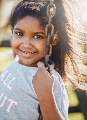 Portrait, joy and girl on swing at park for summer,...
