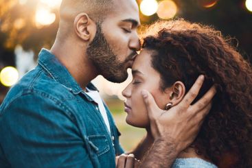 Love, couple and kiss at park together for sunset date,...