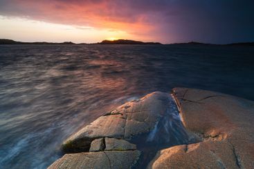 Sunset over serene seascape in Sweden with smooth rocks...